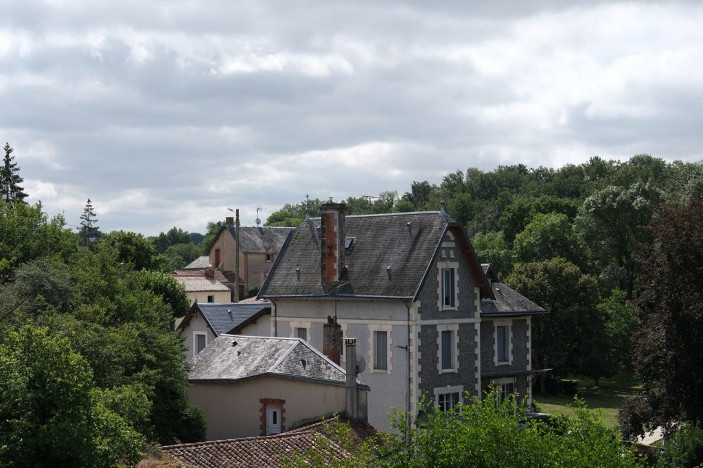 Aerial view of historic houses and lush greenery in a rural French village.
